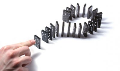 Chain reaction fingers about to touch first domino
